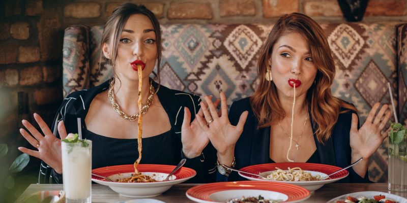 Two women eating pasta in an italian restaurant